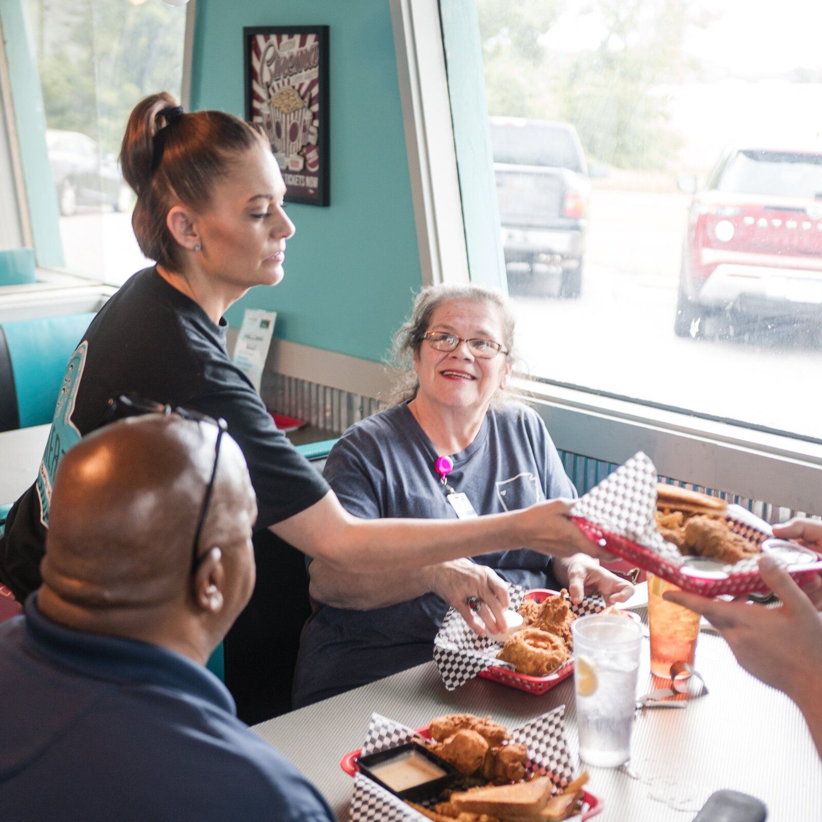A server bringing baskets of food to a table of regulars